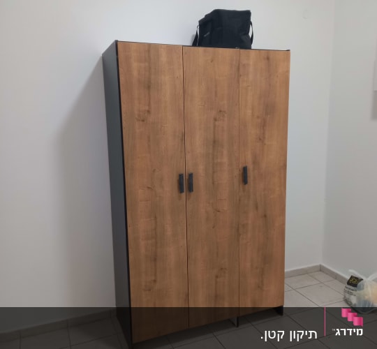 ארון עץ עם שלוש דלתות בחדר ריק
